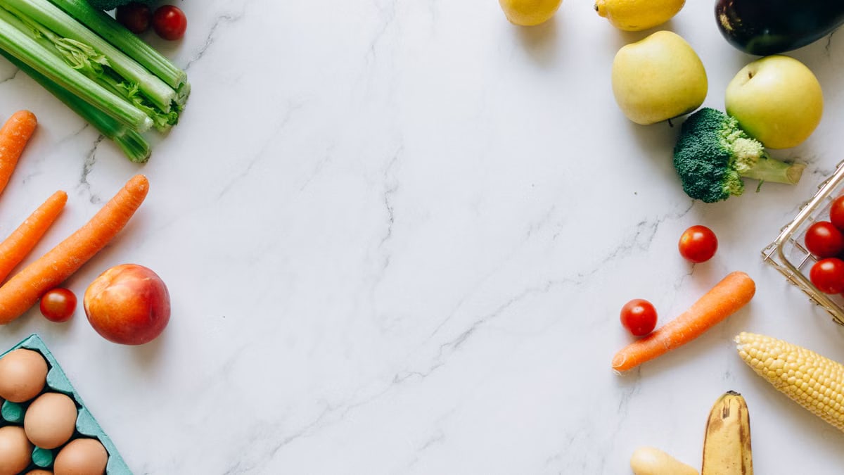 An assortment of fresh fruits and vegetables on a marble background, perfect for healthy lifestyle concepts.